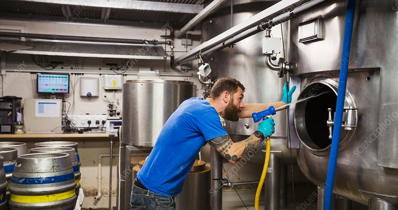 Man working in a brewery, using a hose