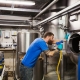 Man working in a brewery, using a hose