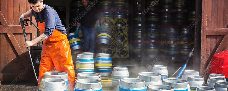 Man working, cleaning metal beer kegs