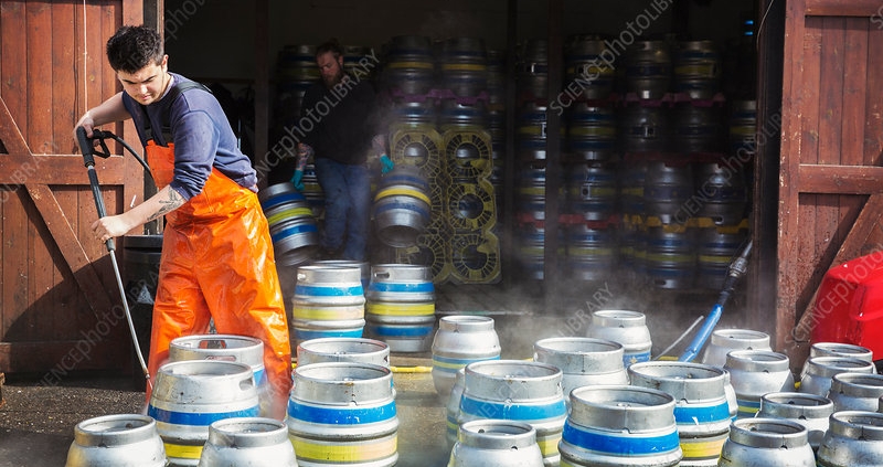 Man working, cleaning metal beer kegs